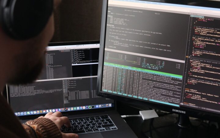 Programador trabalhando em dois monitores