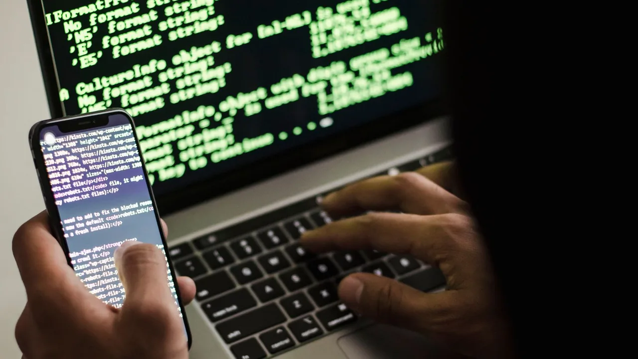 Pessoa usando celular e notebook, em uma cena que representa cuidados de segurança digital