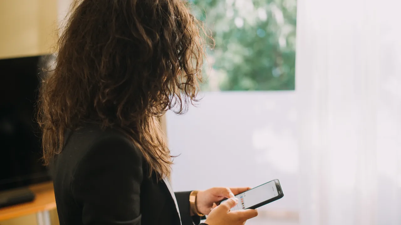 Profissional segurando um smartphone e digitando mensagens, exemplo de atendimento por WhatsApp