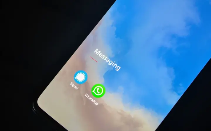 Celular exibindo aplicativos de mensagens, incluindo WhatsApp, em uma mesa