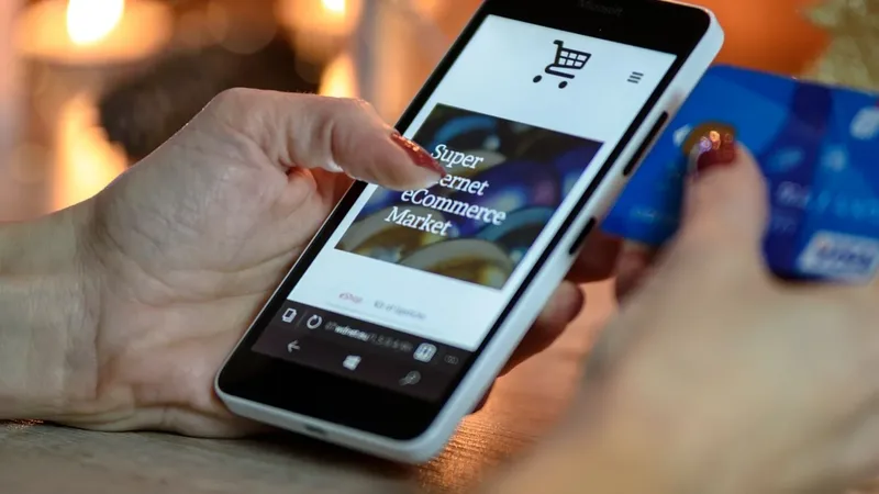 Pessoa usando celular durante uma compra online com cartão na mão