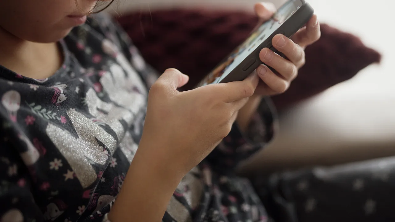 Criança usando smartphone no sofá, exemplo de uso supervisionado