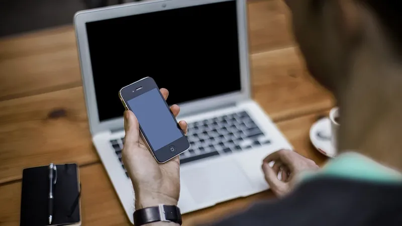 Pessoa usando smartphone e notebook para organizar conversas do Telegram