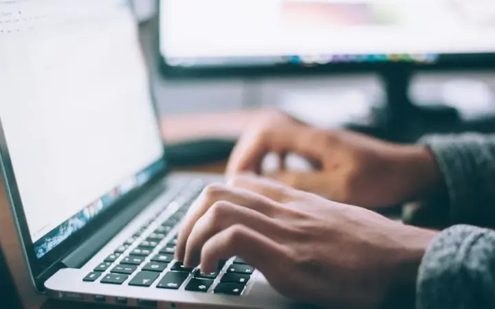 Pessoa trabalhando em um notebook com e-mails na tela, imagem de capa sobre respostas automáticas no Gmail