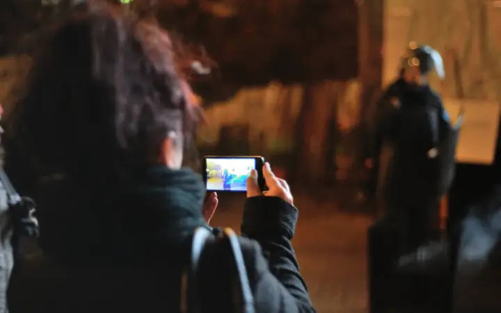 Pessoa usando o celular para fotografar um documento sobre a mesa