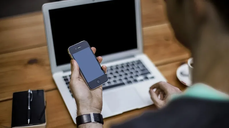 Pessoa segura um celular ao lado de um notebook para ilustrar a transferência de arquivos entre Android e Windows