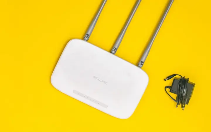 Roteador Wi-Fi branco com antenas sobre fundo amarelo