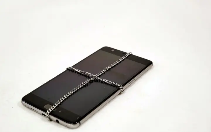 Smartphone preso por uma corrente, ilustrando a proteção do backup criptografado do WhatsApp