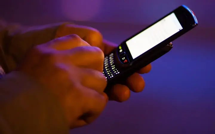 Pessoa segurando um celular enquanto digita mensagens