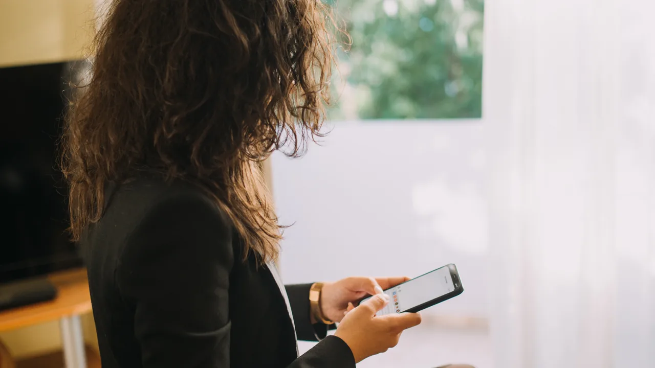 Pessoa digitando mensagens no smartphone durante um atendimento comercial