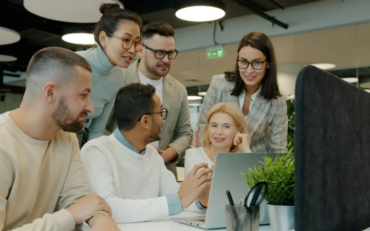 Equipe colaborando diante de um notebook em um escritório
