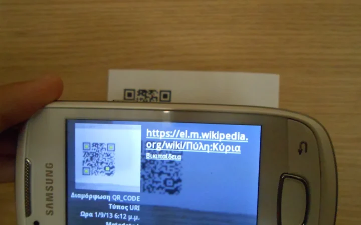 Pessoa usando um celular para escanear um código QR exibido em papel.