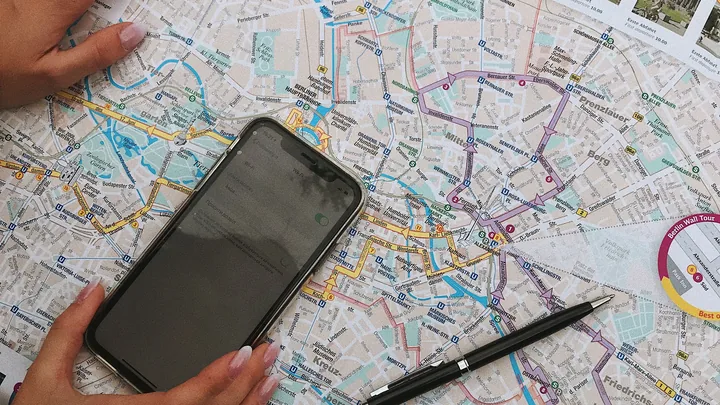 Celular apoiado sobre um mapa impresso, com uma caneta ao lado