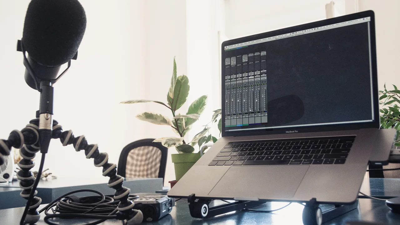 Microfone de estúdio ao lado de um notebook em uma mesa