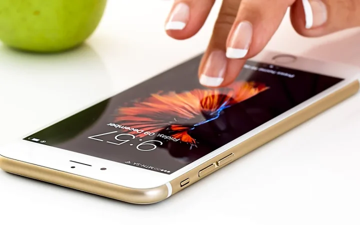 Pessoa tocando a tela de um smartphone em uma mesa