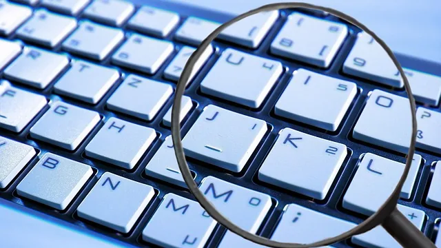 Lupa sobre um teclado representa a pesquisa de e-mails no Outlook