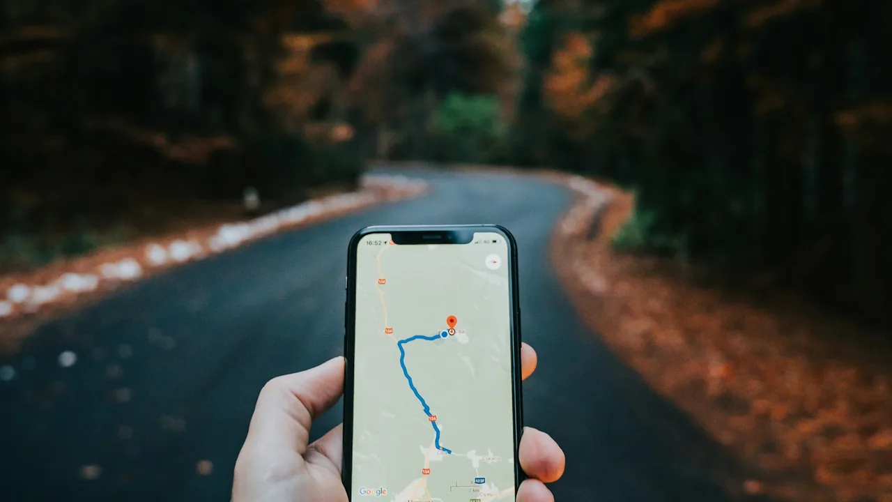 Celular com uma rota de navegação exibida diante de uma estrada