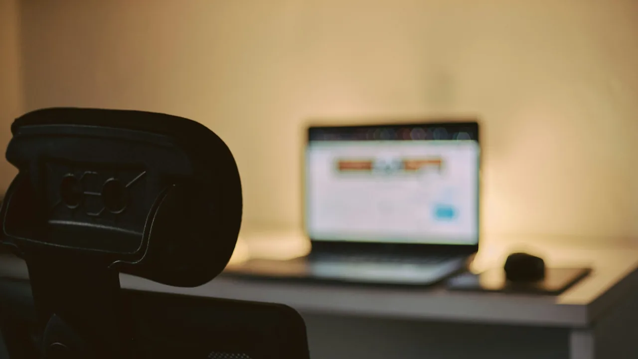 Notebook e monitor em um ambiente de trabalho com pouca luz