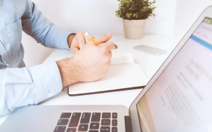 Profissional trabalhando com notebook e caderno em uma mesa