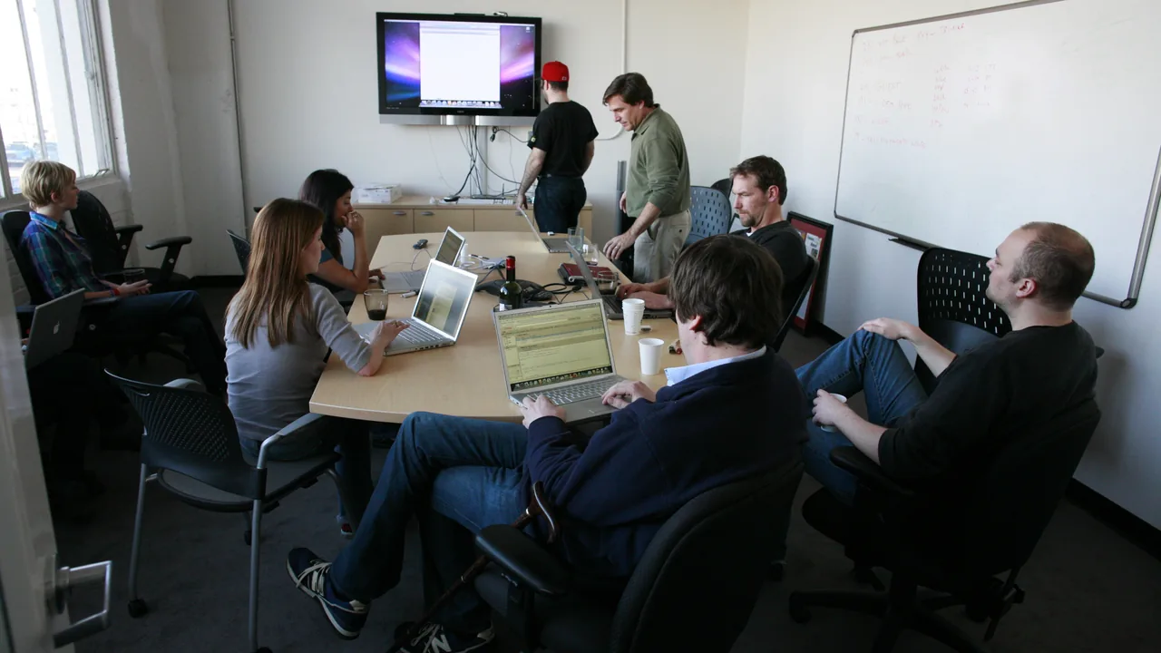 Equipe trabalhando em laptops durante uma reunião, representando a colaboração em uma planilha compartilhada